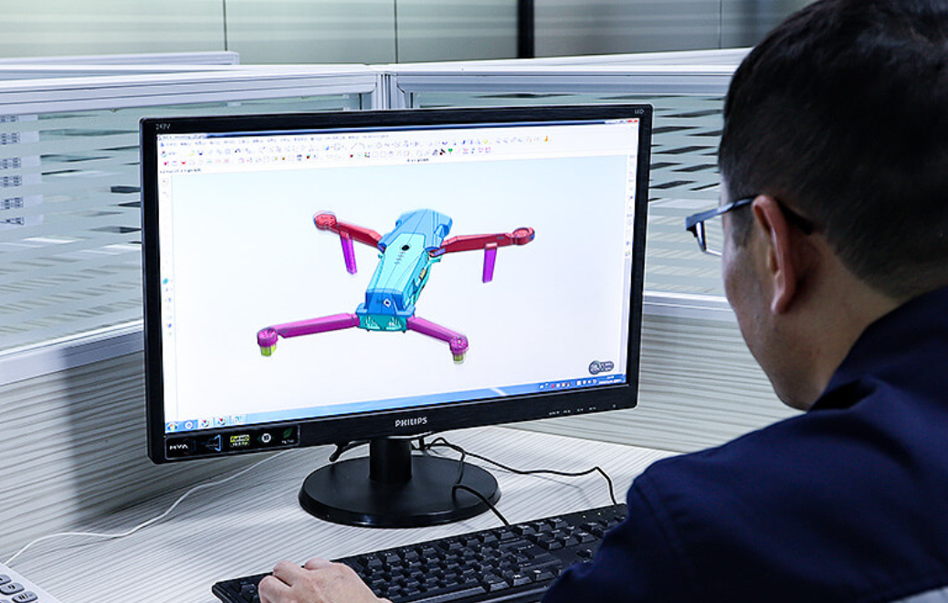 A real engineering design review: product CAD on a large monitor with engineers reviewing functional requirements, interfaces, and component geometry.
